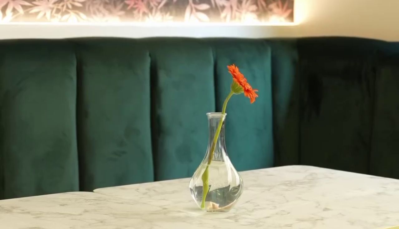 Un vaso con un fiore arancione in mezzo al tavolo nel ristorante - bar Eclipse