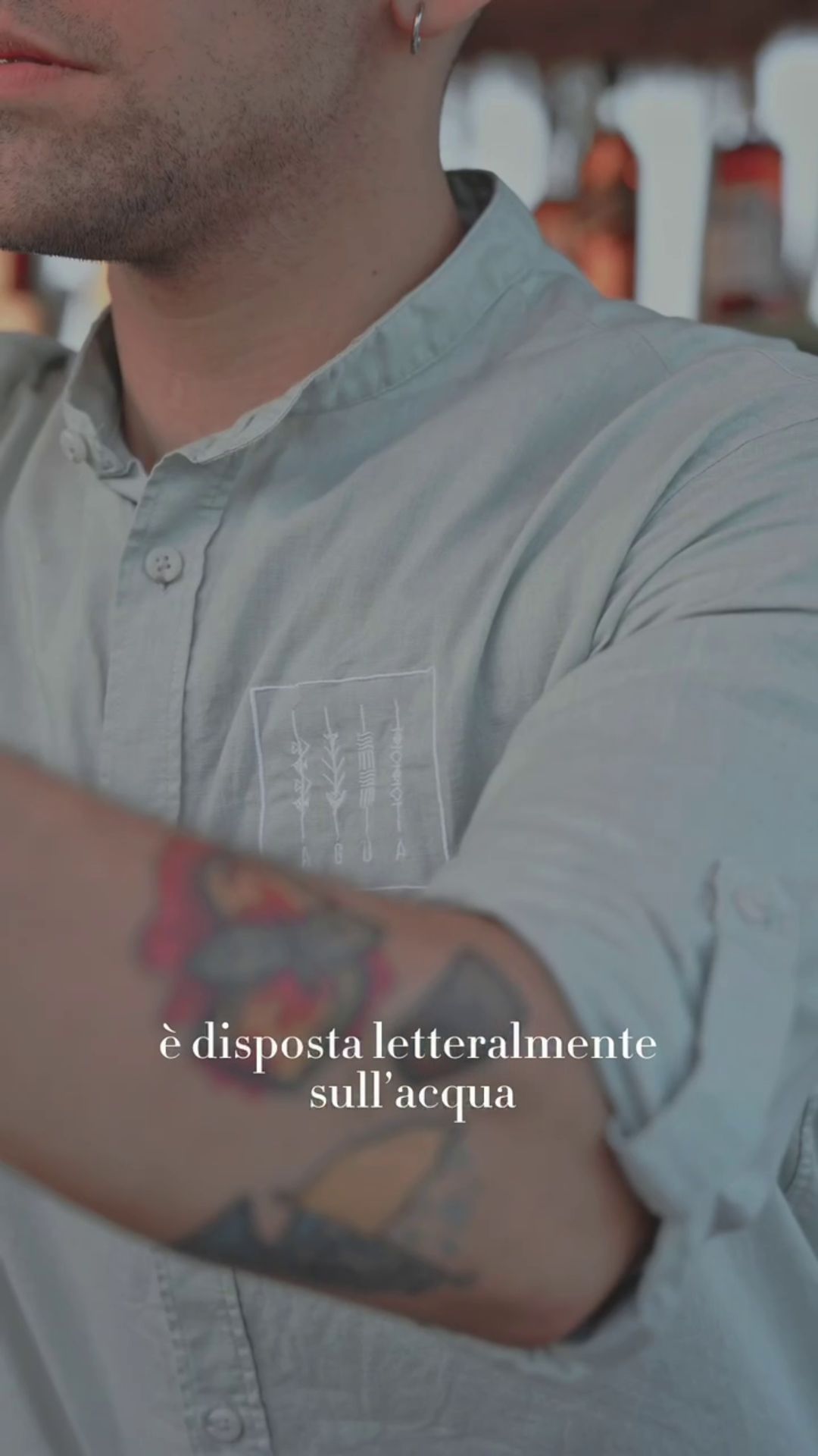 Un cameriere con tatuaggi sul braccio indossa una camicia personalizzata per il churrascheria Agua da Raimonda Lai.